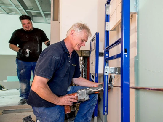 Handwerker installieren Sanitäranlagen beim Trockenbau in einem modernen Innenausbau.