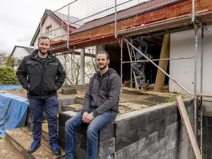 Zwei Männer stehen vor einem Haus mit Gerüst bei einer energetischen Haussanierung.