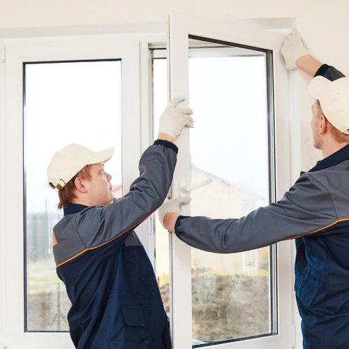 Zwei Handwerker montieren ein neues Fenster im Rahmen für energieeffiziente Renovierung.