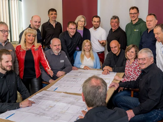 Gruppe von Architekten und Planern bespricht Baupläne bei einem Teammeeting im Büro.